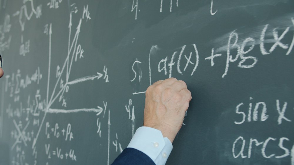 Teacher writing maths formulas on a chalkboard